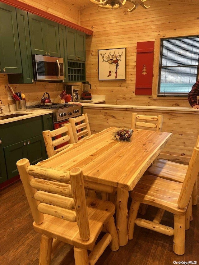 dining area featuring hardwood / wood-style floors, sink, and wooden walls