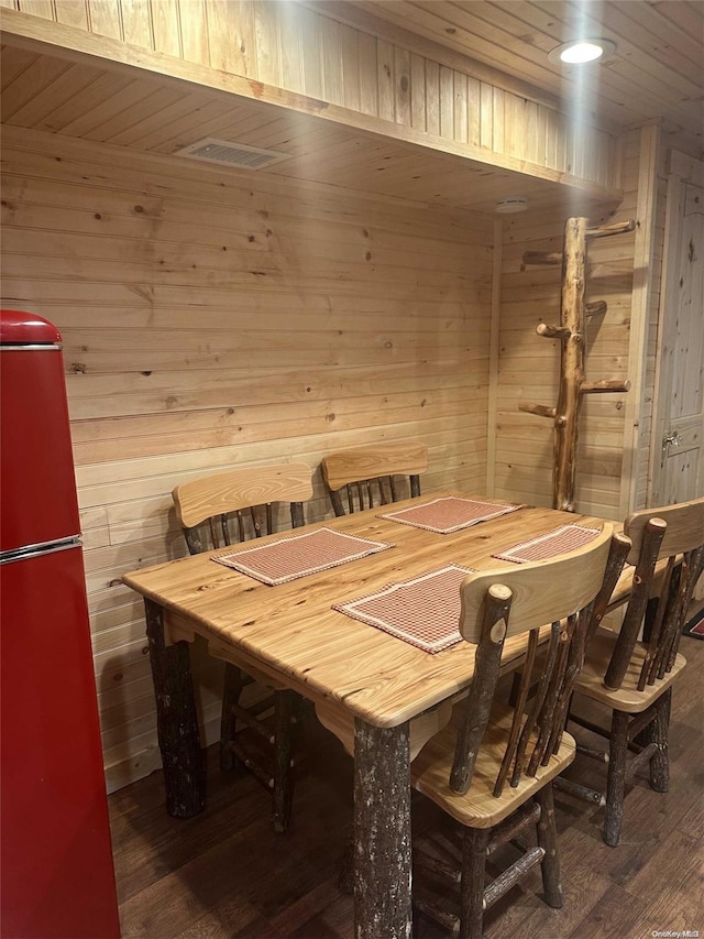 dining room featuring dark hardwood / wood-style flooring and wood walls