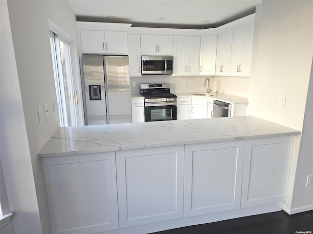 kitchen featuring white cabinets, stainless steel appliances, and light stone counters