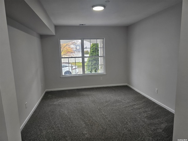 spare room with dark colored carpet