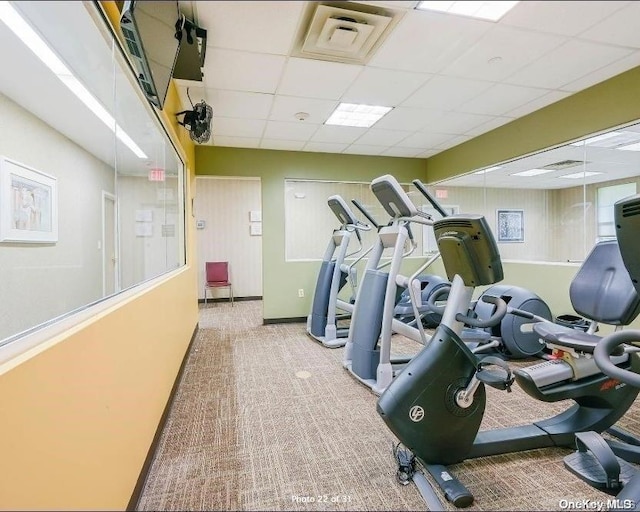 exercise room featuring a paneled ceiling and carpet