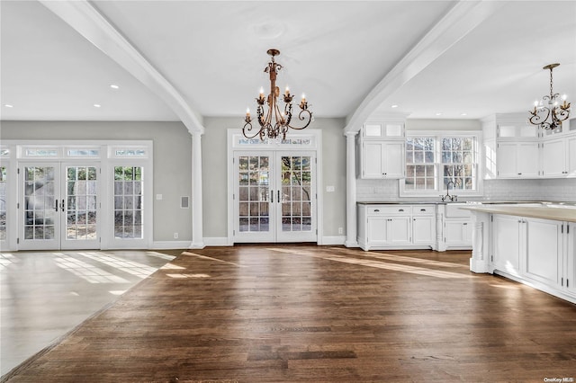 unfurnished dining area with french doors, dark hardwood / wood-style floors, a chandelier, and beamed ceiling