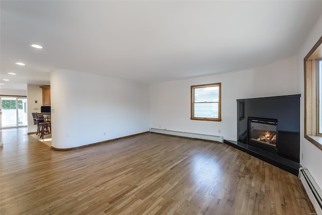 unfurnished living room featuring hardwood / wood-style flooring and baseboard heating