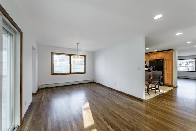 unfurnished living room with baseboard heating, dark hardwood / wood-style flooring, and an inviting chandelier