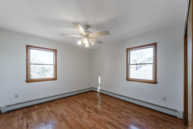 empty room with a healthy amount of sunlight, wood-type flooring, and a baseboard radiator