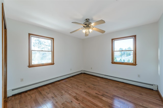 empty room featuring baseboard heating, a wealth of natural light, ceiling fan, and hardwood / wood-style flooring