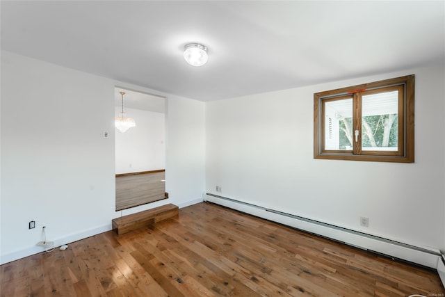 empty room featuring hardwood / wood-style flooring and a baseboard heating unit