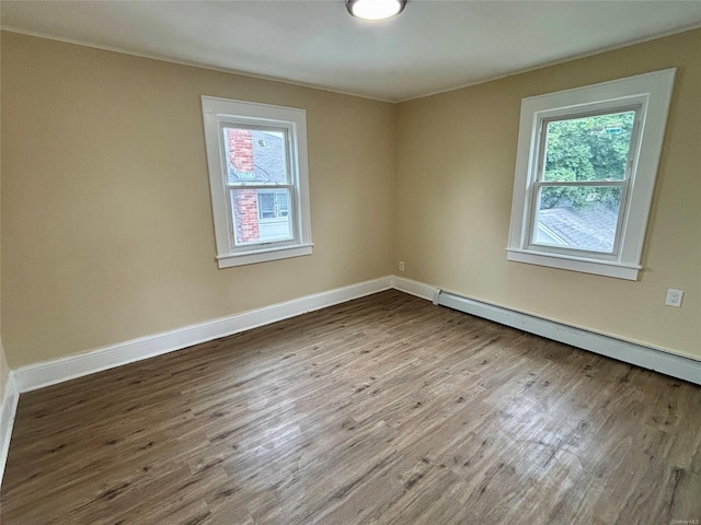 18 Perry St, Hempstead, NY 11550 - unfurnished room with healthy amount of natural light, baseboard heating, and wood finished floors