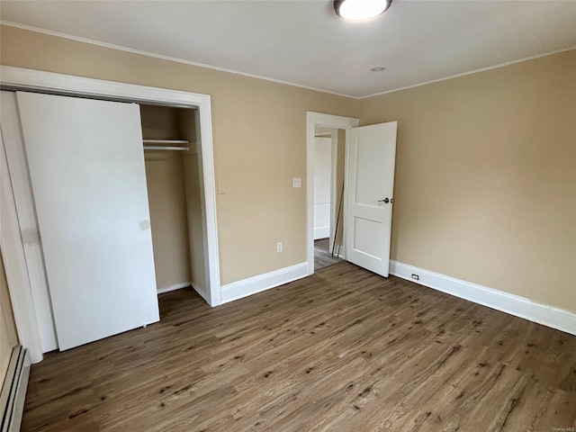 18 Perry St, Hempstead, NY 11550 - unfurnished bedroom with crown molding, baseboard heating, wood finished floors, a closet, and baseboards