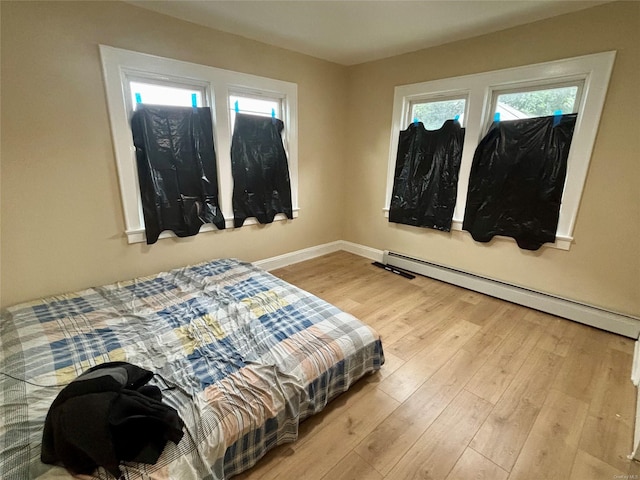 18 Perry St, Hempstead, NY 11550 - bedroom with wood finished floors, a baseboard heating unit, multiple windows, and baseboards
