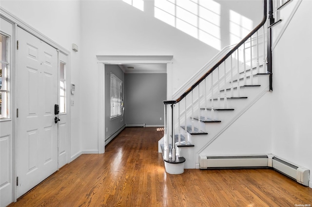 entryway featuring a healthy amount of sunlight, wood-type flooring, and a baseboard heating unit