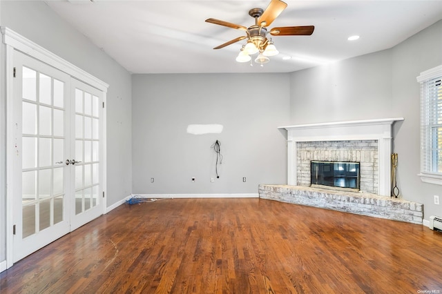 unfurnished living room with a fireplace, french doors, hardwood / wood-style flooring, and ceiling fan