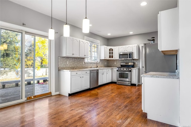 kitchen featuring white cabinetry, sink, hanging light fixtures, stainless steel appliances, and dark hardwood / wood-style flooring