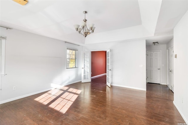 empty room featuring french doors, dark hardwood / wood-style floors, and an inviting chandelier