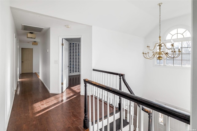 hallway with dark hardwood / wood-style flooring, vaulted ceiling, and a notable chandelier