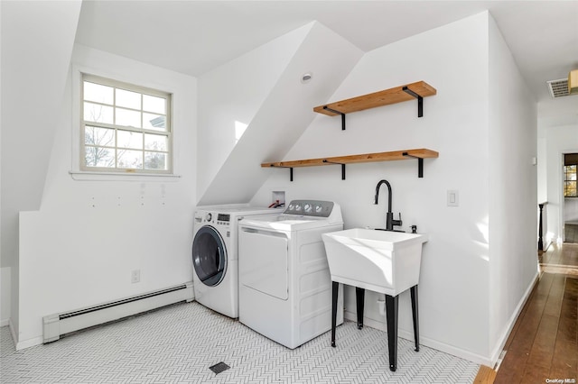 clothes washing area featuring washing machine and dryer, light hardwood / wood-style flooring, and a baseboard heating unit