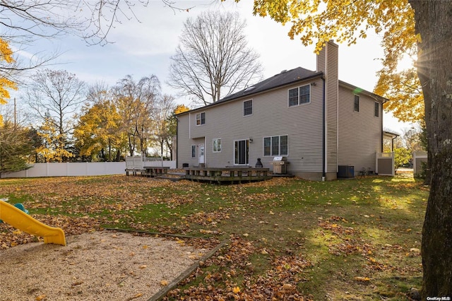 back of property with a yard, a playground, central AC, and a wooden deck