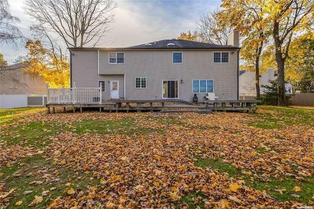 back of property with a deck and a lawn