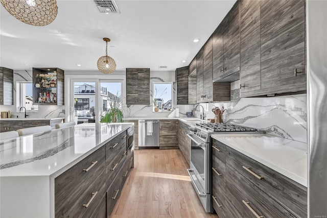 kitchen with sink, pendant lighting, stainless steel appliances, and light hardwood / wood-style floors