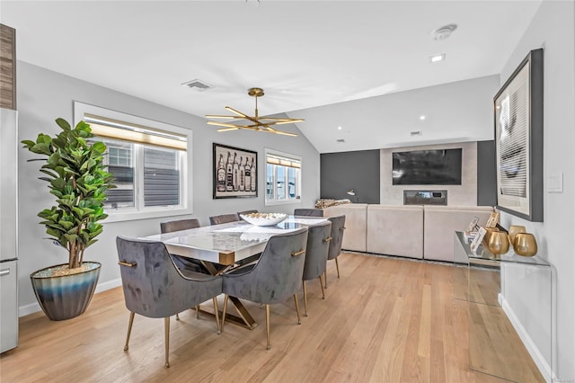 dining area featuring light hardwood / wood-style floors, vaulted ceiling, and a notable chandelier