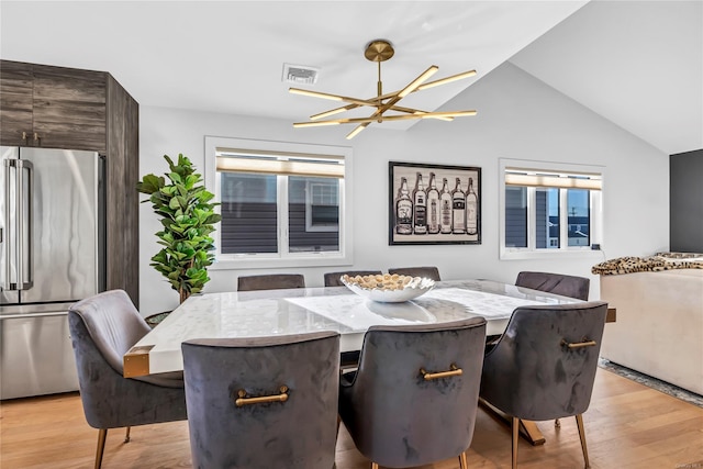 dining room with light hardwood / wood-style flooring, lofted ceiling, and a notable chandelier