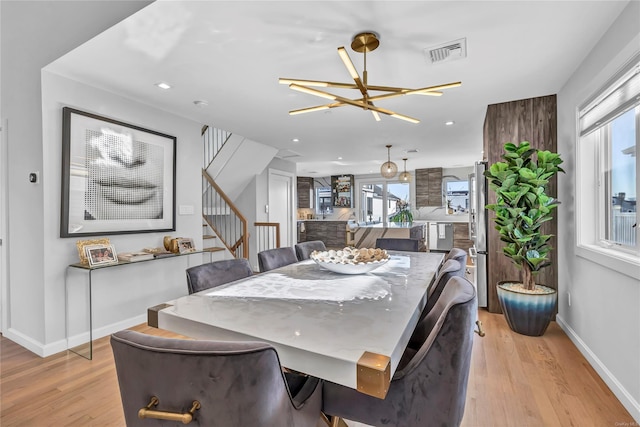 dining space with light hardwood / wood-style floors and an inviting chandelier