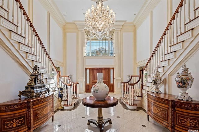 entrance foyer featuring a towering ceiling, ornamental molding, light tile patterned floors, and a chandelier