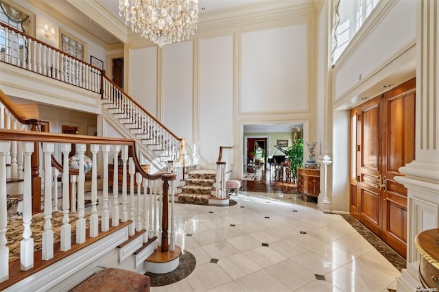 foyer with a high ceiling, light tile patterned floors, an inviting chandelier, and ornamental molding