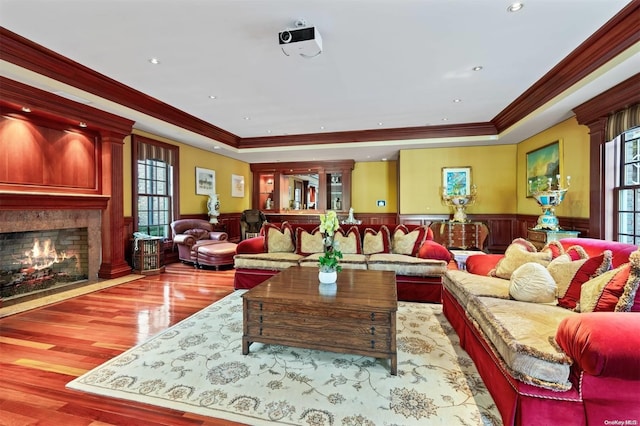 living room with crown molding, a premium fireplace, and light wood-type flooring