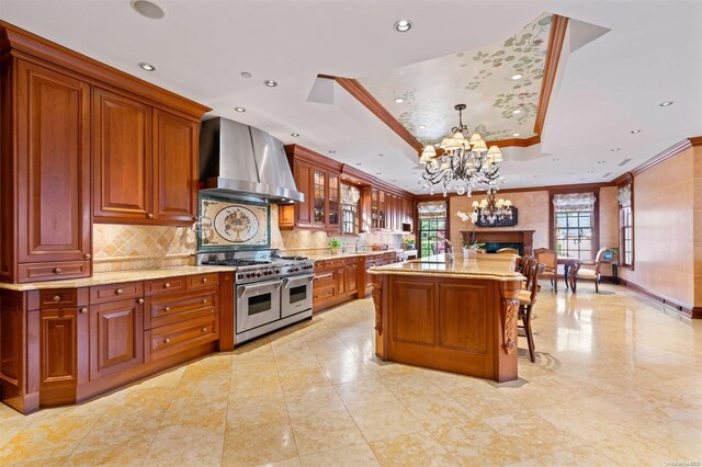 660 Chicken Valley Rd, Matinecock, NY 11560 - kitchen featuring wall chimney exhaust hood, double oven range, ornamental molding, a chandelier, and a raised ceiling