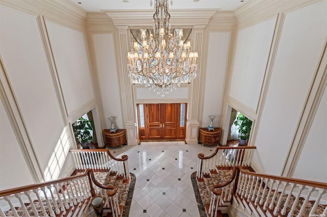 foyer with crown molding, a chandelier, and a high ceiling