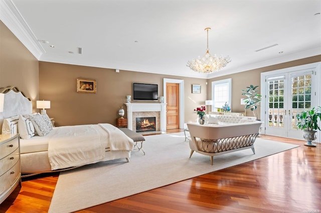 bedroom featuring access to outside, light hardwood / wood-style floors, and ornamental molding