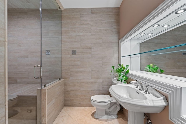 bathroom with tile patterned flooring, toilet, a shower with shower door, and tile walls