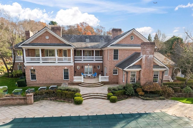 rear view of house featuring a patio area, a balcony, and a covered pool