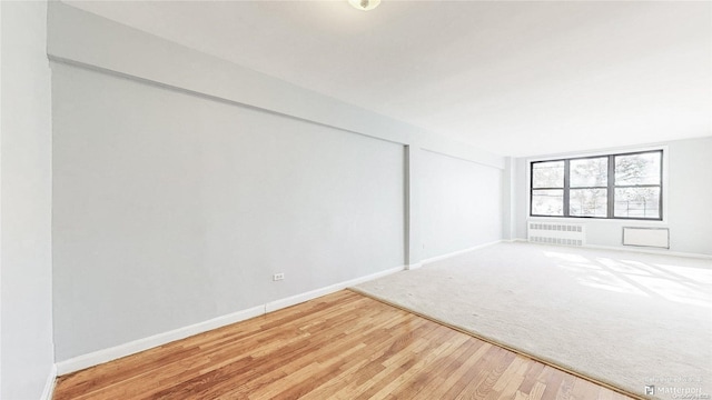 empty room featuring radiator and hardwood / wood-style flooring