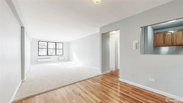 empty room with light hardwood / wood-style floors and radiator