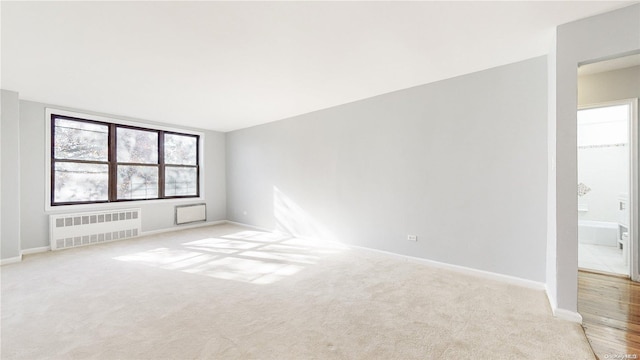 carpeted spare room featuring radiator