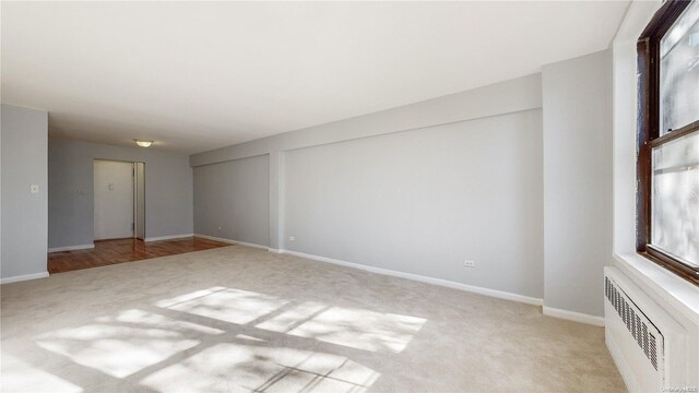 carpeted empty room featuring radiator heating unit