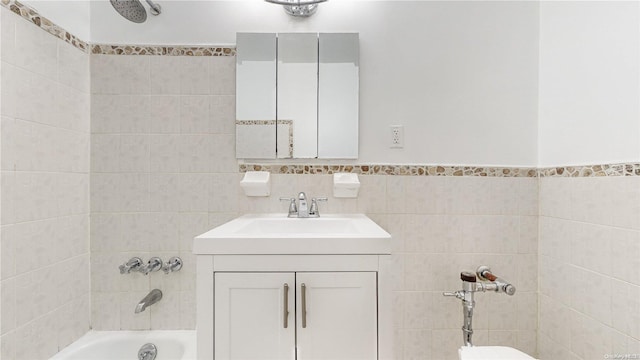 bathroom with tiled shower / bath combo, tile walls, and vanity