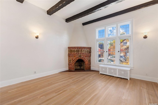 unfurnished living room with radiator, a fireplace, beamed ceiling, and light wood-type flooring