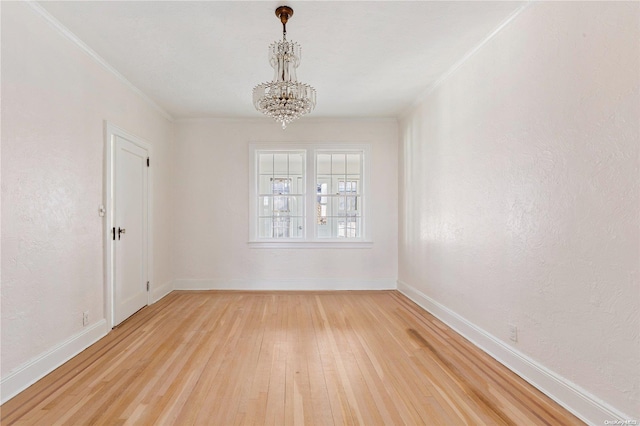 unfurnished room with hardwood / wood-style flooring, ornamental molding, and an inviting chandelier