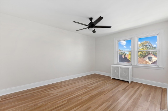 empty room featuring radiator, ceiling fan, and light hardwood / wood-style floors