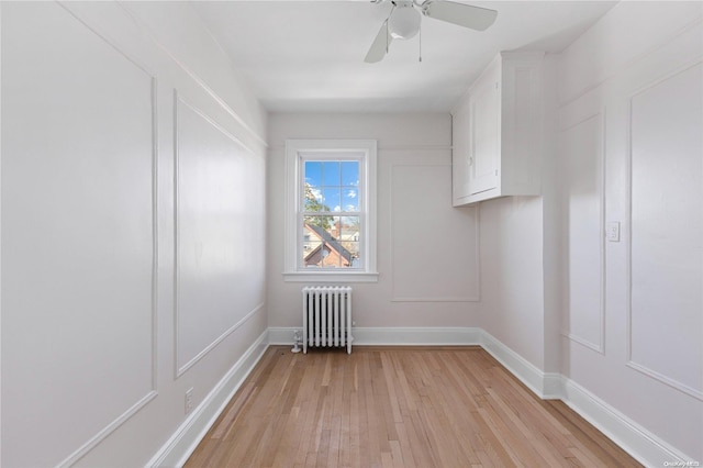 empty room with ceiling fan, radiator heating unit, and light hardwood / wood-style floors