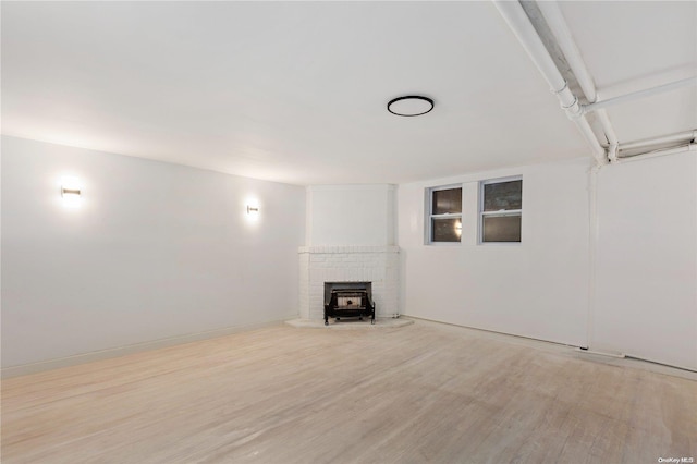 basement featuring a wood stove and light wood-type flooring