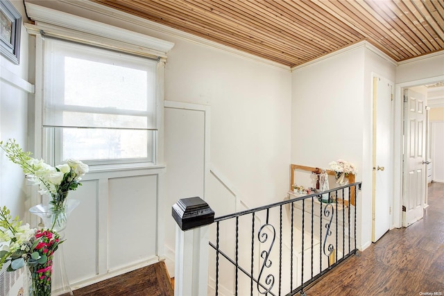 hallway featuring ornamental molding, dark wood-type flooring, and wooden ceiling