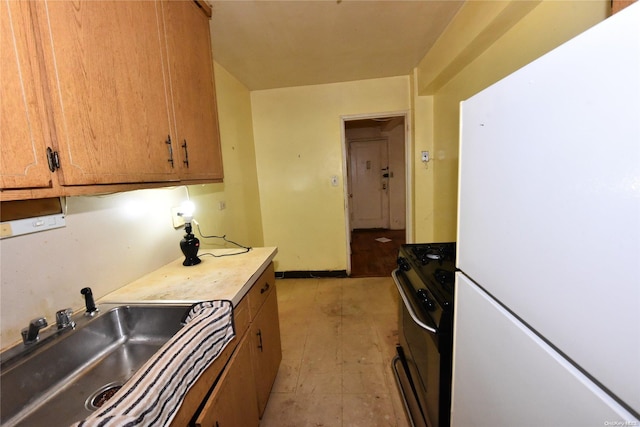 kitchen with stainless steel range, white fridge, and sink