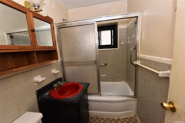 full bathroom with tile patterned flooring, combined bath / shower with glass door, toilet, vanity, and tile walls