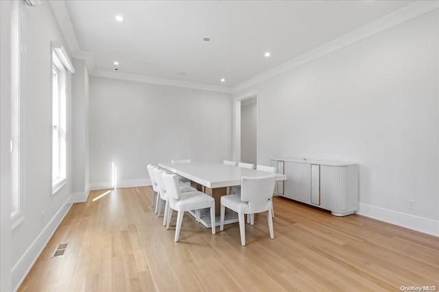 dining area with ornamental molding and light wood-type flooring