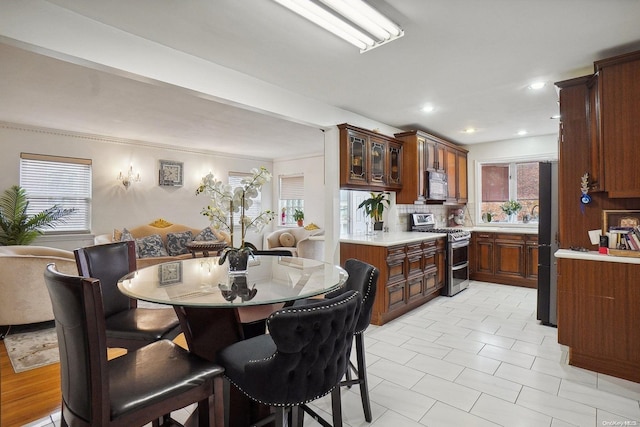 kitchen featuring a breakfast bar, backsplash, stainless steel appliances, and crown molding