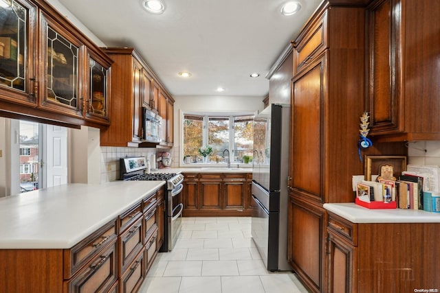 kitchen with decorative backsplash, light tile patterned floors, stainless steel appliances, and sink